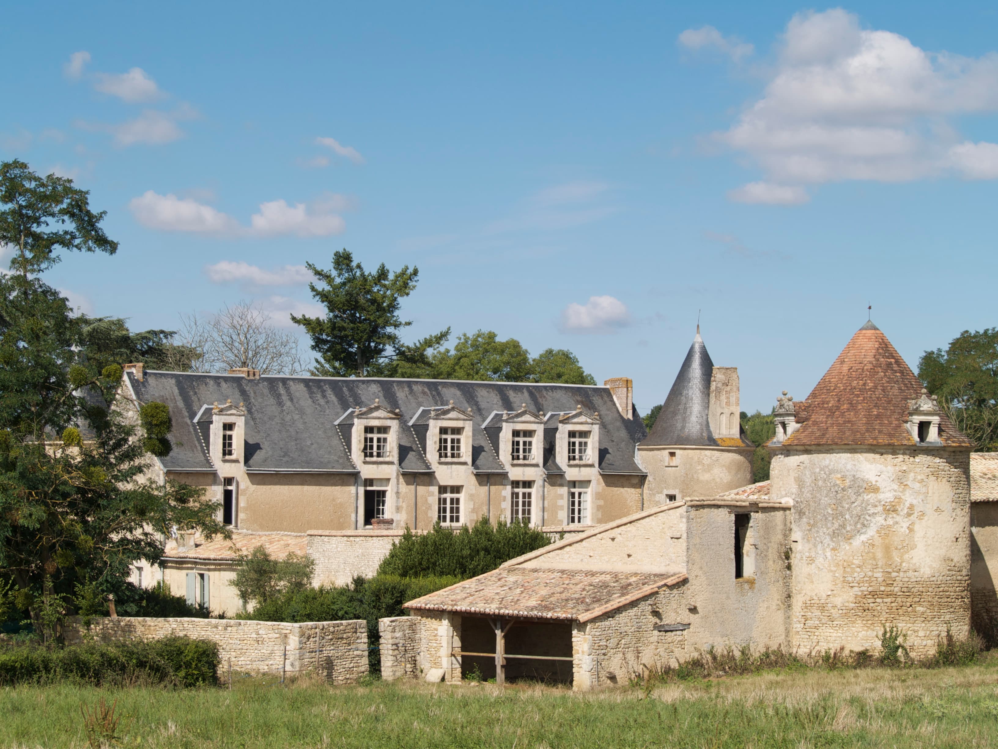 Le château de l'Herbaudière à Saivres, façade de pierre et tour ronde sous un ciel d'été